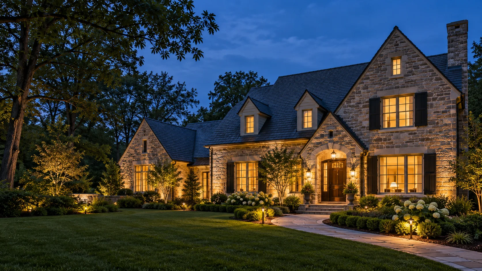 Illustrative stone home with warm exterior lighting at dusk